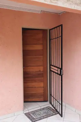 a wooden door in a building with a gate at Thenjwas Sleep-Over Lodge in Nelspruit