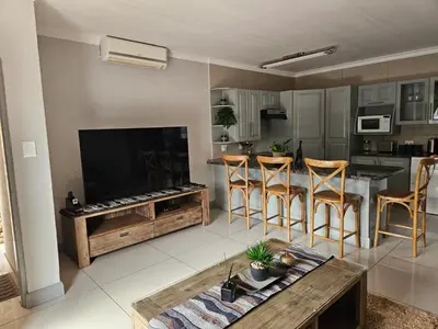 a living room with a large television and a table at Cranes Nest Guest House in Pretoria