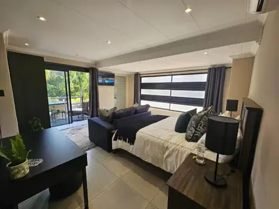 a bedroom with a bed and a couch and a table at Cranes Nest Guest House in Pretoria
