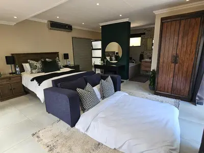 a large bedroom with a bed and a couch at Cranes Nest Guest House in Pretoria