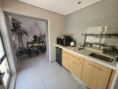 a small kitchen with a sink and a microwave at Cranes Nest Guest House in Pretoria