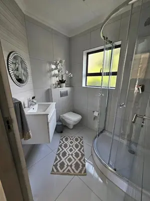 a bathroom with a shower and a toilet and a sink at Cranes Nest Guest House in Pretoria