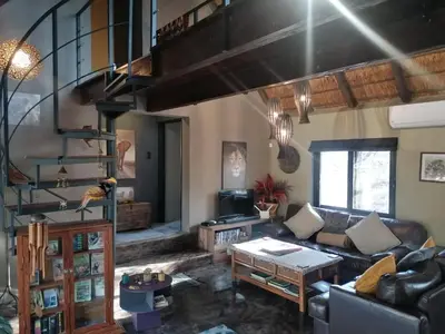 a living room with a couch and a spiral staircase at Lions Gate in Marloth Park