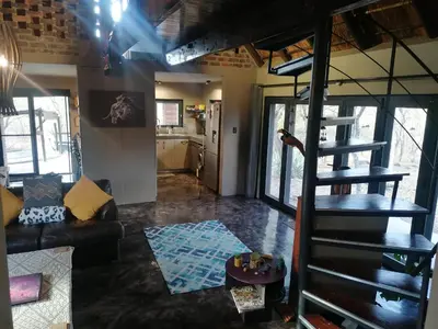 a living room with a spiral staircase in a loft at Lions Gate in Marloth Park