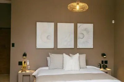 a bedroom with a bed with four pictures on the wall at Leopard's Villa, Marloth Park in Marloth Park