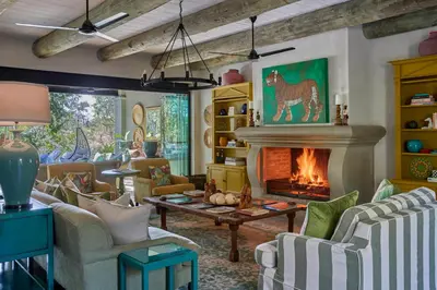 a living room with a fireplace and a couch and chairs at Royal Malewane in Thornybush Game Reserve