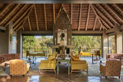 a living room with yellow chairs and a table at Royal Malewane in Thornybush Game Reserve
