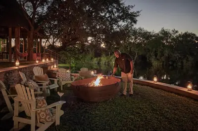 a man standing in front of a fire pit at Royal Malewane in Thornybush Game Reserve