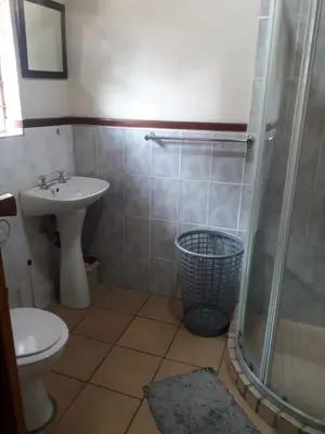 a bathroom with a toilet and a sink and a shower at Jolly Suites in Midrand
