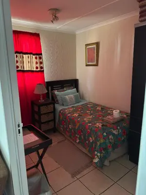 a bedroom with a bed and a table with a lamp at Jolly Suites in Midrand