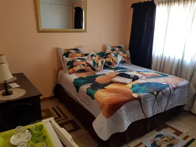 a bedroom with a bed with a blanket and a mirror at Jolly Suites in Midrand