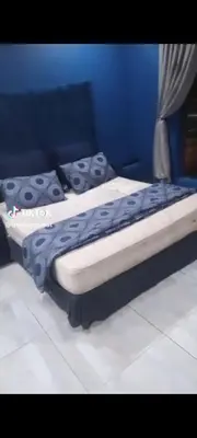 two beds in a bedroom with a blue wall at Budias Guesthouse B&B in Kempton Park