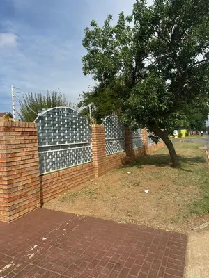 a brick fence with a tree in front of it at Safaya Inn in Kempton Park