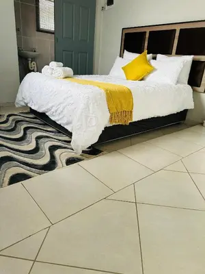 a bedroom with a bed with a yellow and white blanket at Safaya Inn in Kempton Park
