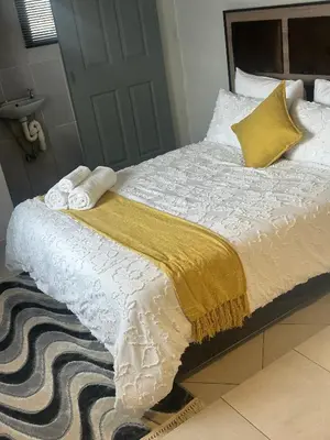 a bed with a yellow and white blanket and pillows at Safaya Inn in Kempton Park