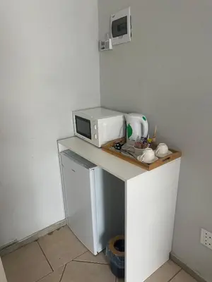 a small kitchen with a microwave and a small refrigerator at Safaya Inn in Kempton Park