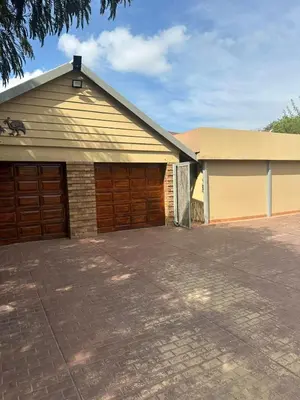 a garage with two brown garage doors and a driveway at Safaya Inn in Kempton Park