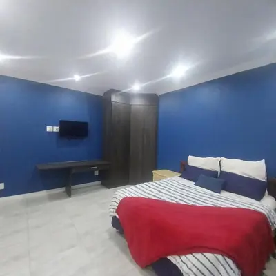 a bedroom with a large bed with a blue wall at Mia's Accomidation in Kempton Park