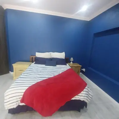 a blue room with a bed with a red blanket at Mia's Accomidation in Kempton Park