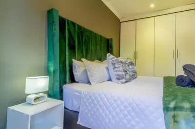 a bedroom with a white bed and a green headboard at Meadow Lane in Johannesburg