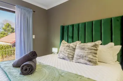 a bedroom with a bed with a green headboard and pillows at Meadow Lane in Johannesburg
