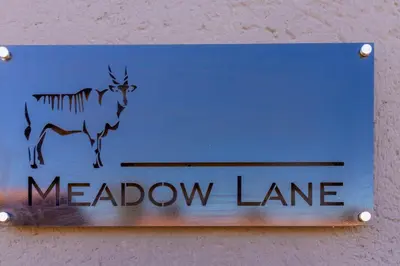 a blue sign with a meadow lane on a wall at Meadow Lane in Johannesburg