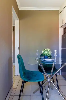a dining room with a glass table and green chairs at Meadow Lane in Johannesburg