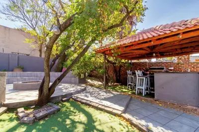 a backyard with a tree and a wooden pergola at Meadow Lane in Johannesburg