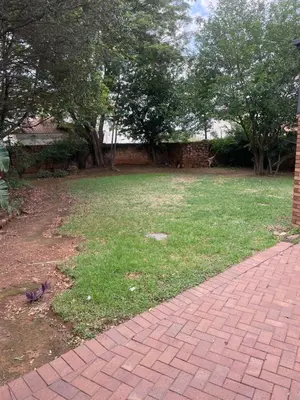 a brick walkway next to a yard with trees at The Ridge in Pretoria