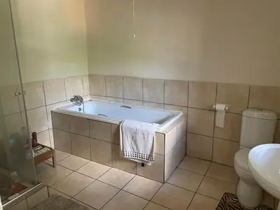 a bathroom with a bath tub and a toilet at The Ridge in Pretoria