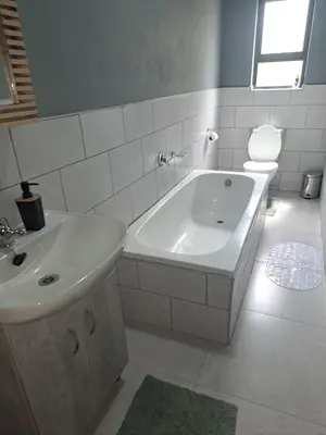 a bathroom with a tub and a sink and a toilet at Selina Guesthouse in Kempton Park