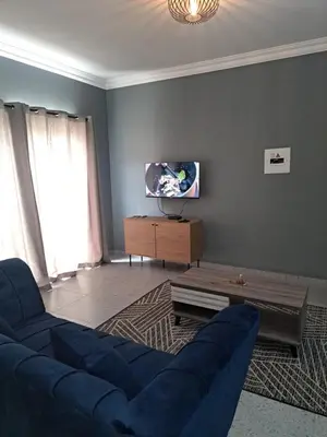 a living room with a blue couch and a tv at Selina Guesthouse in Kempton Park