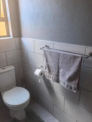 a bathroom with a toilet and towels on a wall at Selina Guesthouse in Kempton Park