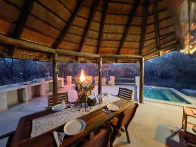 a dining table in a pavilion with a pool at Noah's Ark in Marloth Park