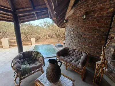 a living room with two couches and a swimming pool at Noah's Ark in Marloth Park