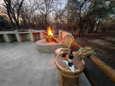 a fire pit with a table and a bottle of wine at Noah's Ark in Marloth Park