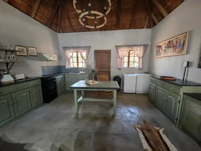 a large kitchen with green cabinets and a table at Noah's Ark in Marloth Park