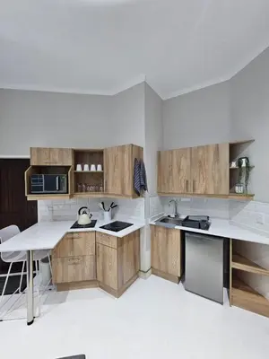 a kitchen with wooden cabinets and a white counter top at Levinia Cottage in Pretoria