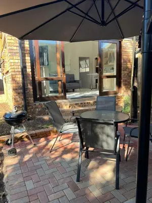 a patio with a table and chairs and an umbrella at Levinia Cottage in Pretoria