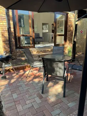 a patio with a table and chairs and an umbrella at Levinia Cottage in Pretoria