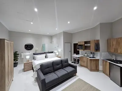 a bedroom with a bed and a couch and a kitchen at Levinia Cottage in Pretoria
