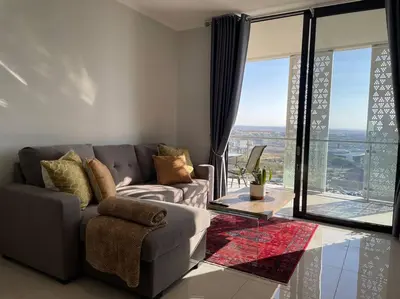 a living room with a couch and a large window at Your Oasis in Waterfall City in Midrand