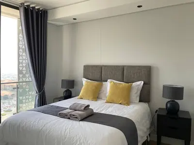 a bedroom with a large white bed with yellow pillows at Your Oasis in Waterfall City in Midrand
