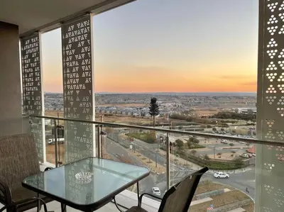 a glass table and chairs in a room with a view at Your Oasis in Waterfall City in Midrand
