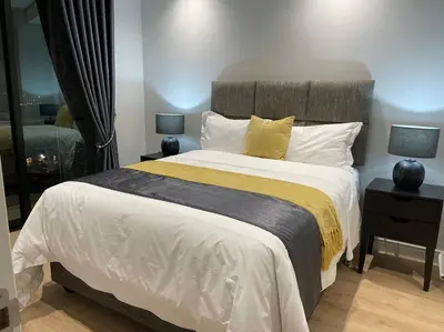 a bedroom with a large bed and two lamps on tables at Your Oasis in Waterfall City in Midrand
