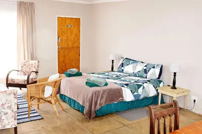 a bedroom with a bed and a table and chairs at Pecan and Lime Inn The Main Den in Pretoria