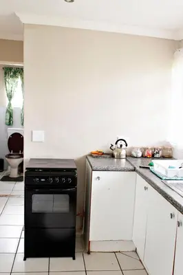 a kitchen with a black stove and white cabinets at Pecan and Lime Inn The Main Den in Pretoria