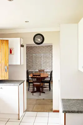 a kitchen with a table and a clock on the wall at Pecan and Lime Inn The Main Den in Pretoria