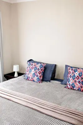a bed with blue and white sheets and pillows at Pecan and Lime Inn The Main Den in Pretoria