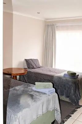 a bedroom with two beds and a table and a window at Pecan and Lime Inn The Main Den in Pretoria